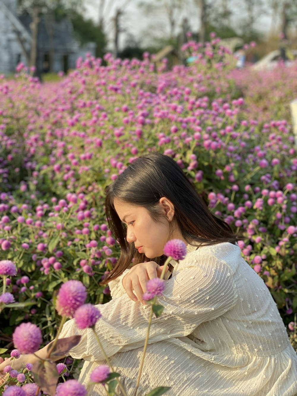 a woman sitting in a field of flowers