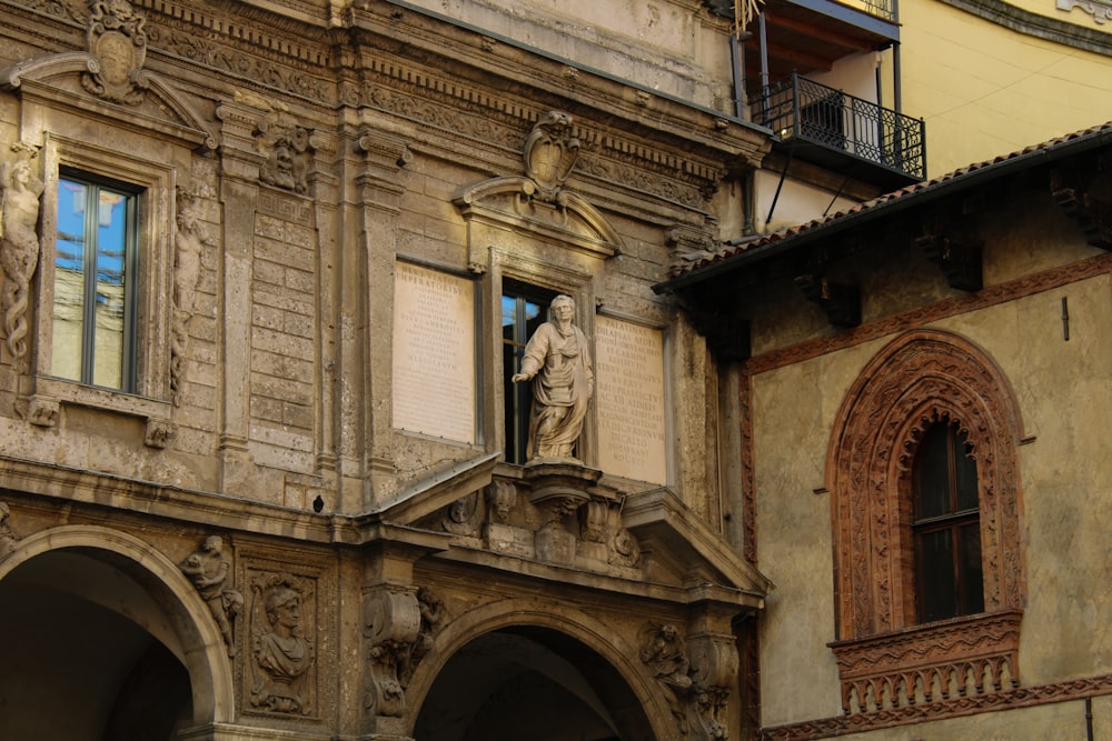 an old building with a statue on the balcony