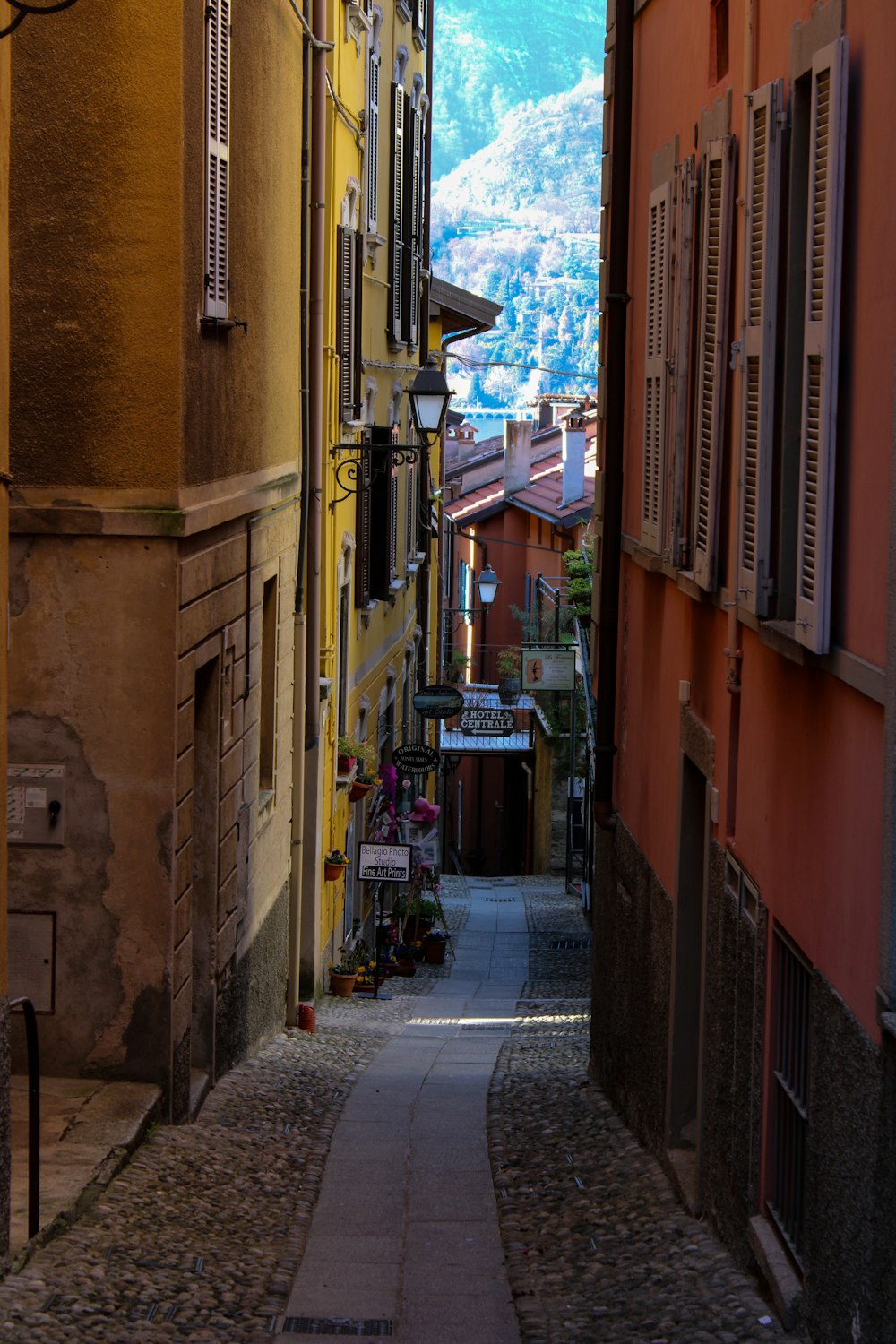 a narrow city street with a mountain in the background