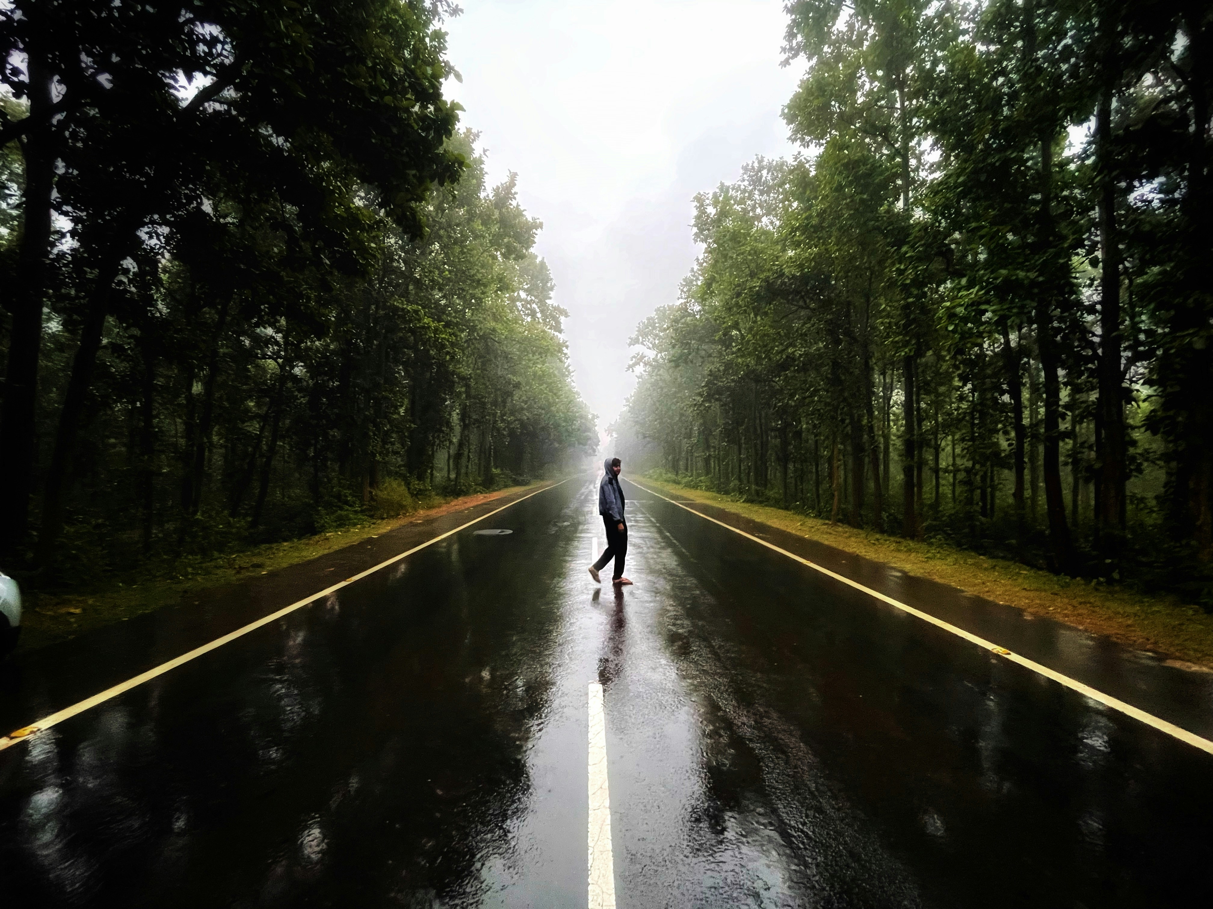 a person standing in the middle of a road in the rain