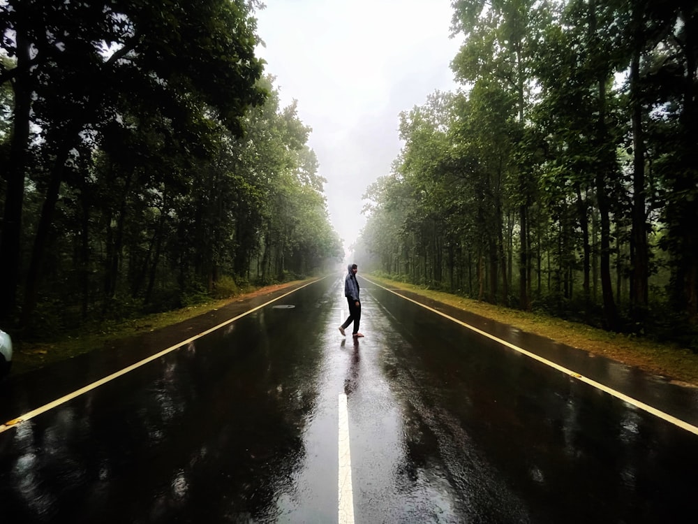 a person standing in the middle of a road in the rain