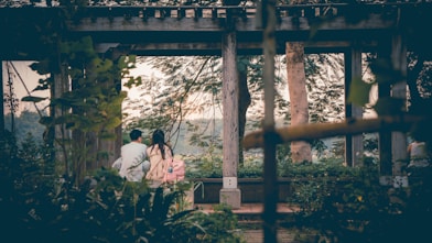a couple of people standing under a wooden structure