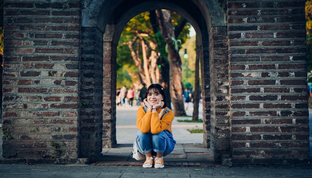 a young girl sitting on the ground in front of an archway