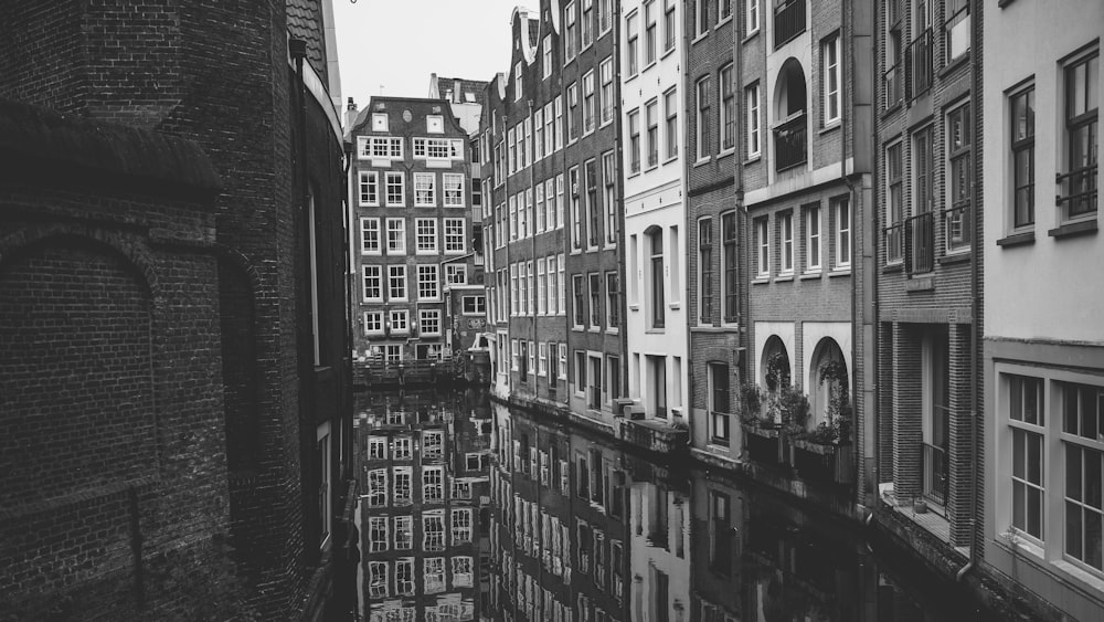 a black and white photo of a canal in a city