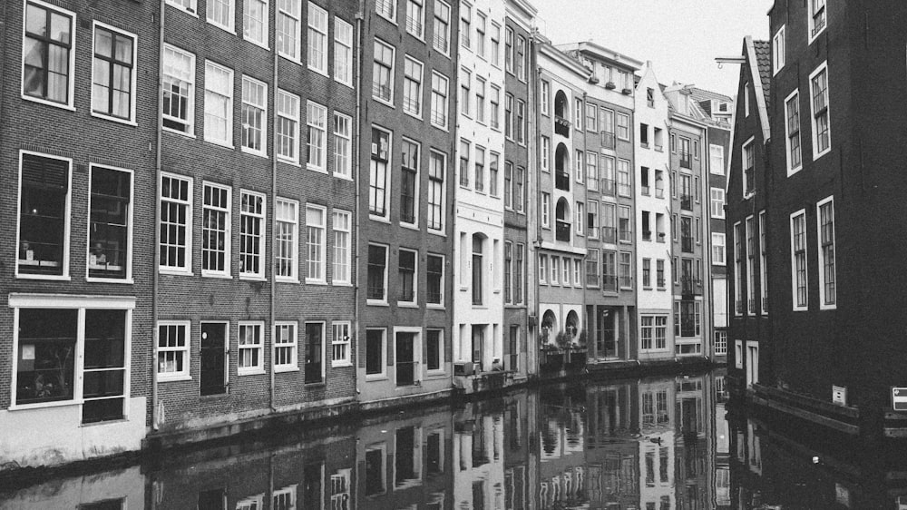 a black and white photo of a canal in a city