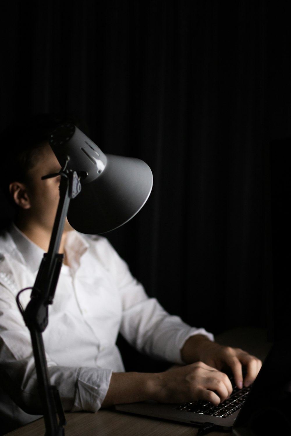 a man sitting at a desk with a laptop in front of a microphone