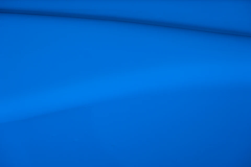 Close-up view of blue fabric with slight sheen, folded over itself in texture