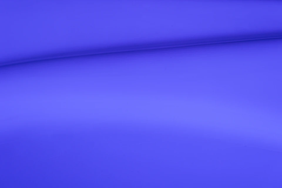 Close-up view of a blue, curved fabric with subtle wrinkles and blurred background