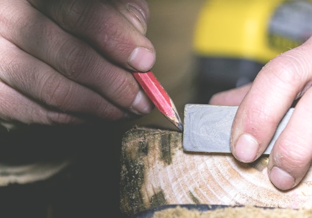 a person using a pencil to cut a piece of wood