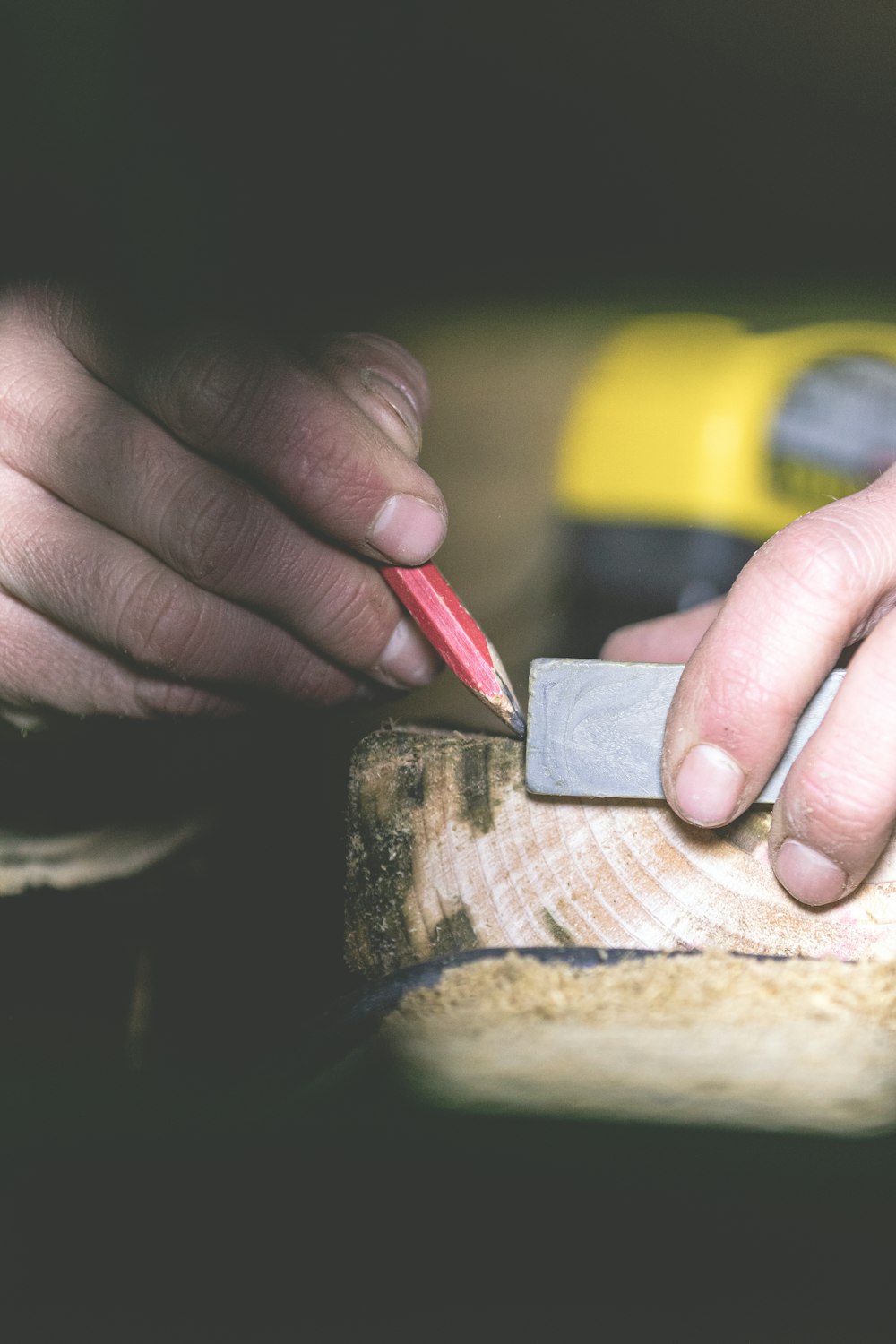 Eine Person, die einen Bleistift benutzt, um ein Stück Holz zu schneiden