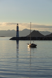 a sailboat in the water near a light house