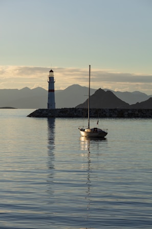 a sailboat in the water near a light house