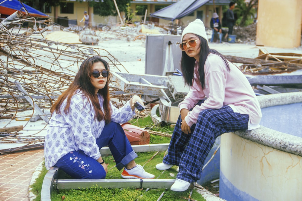 two women sitting on a ledge in front of a building