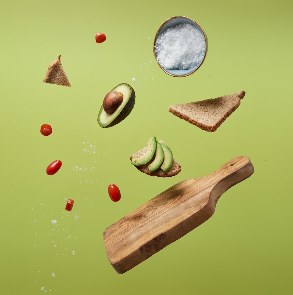 geschnittene Avocado, Tomaten und Brot auf einer grünen Oberfläche