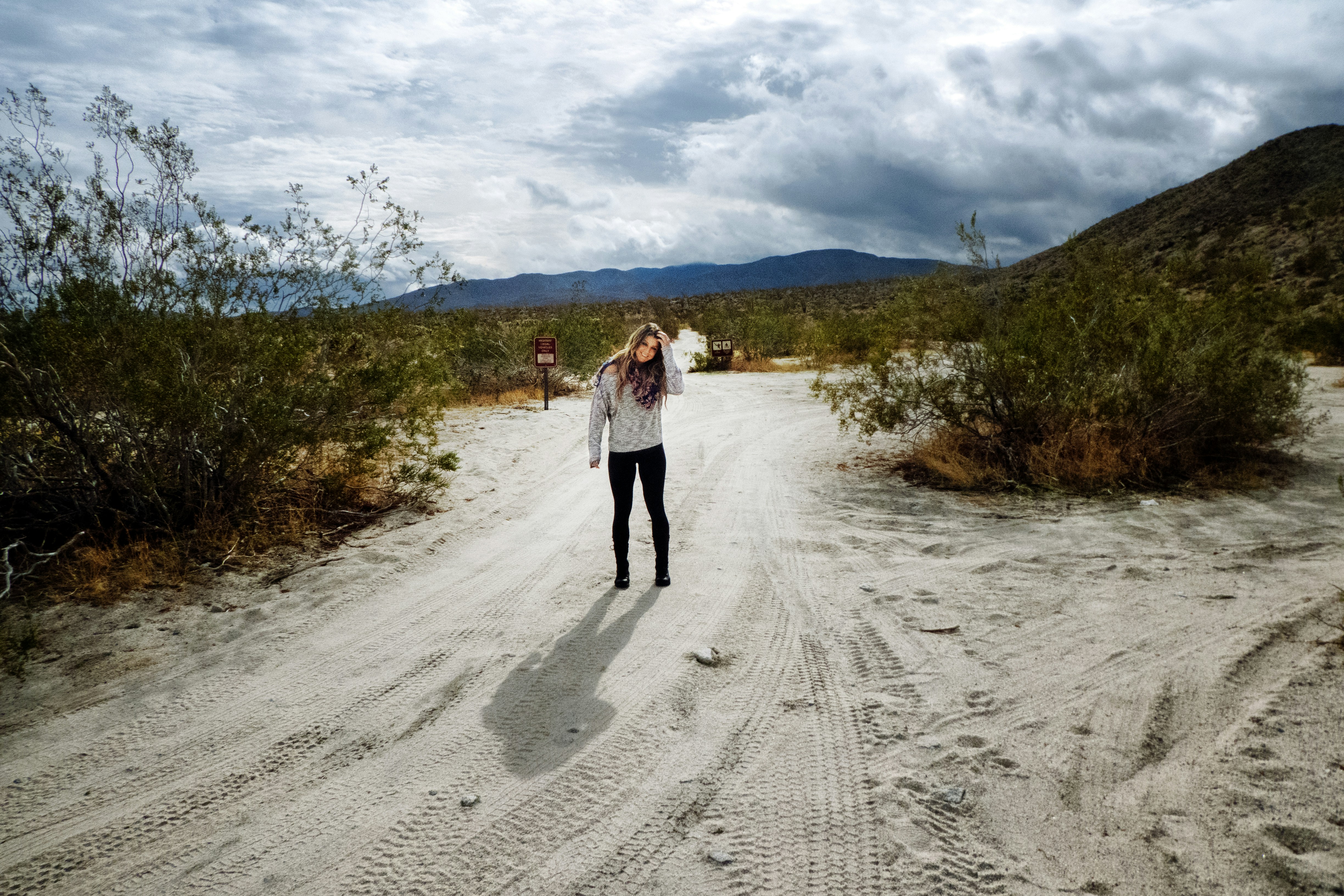 a woman walking down a dirt road in the desert