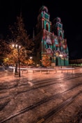 a church lit up at night with a train track in front of it