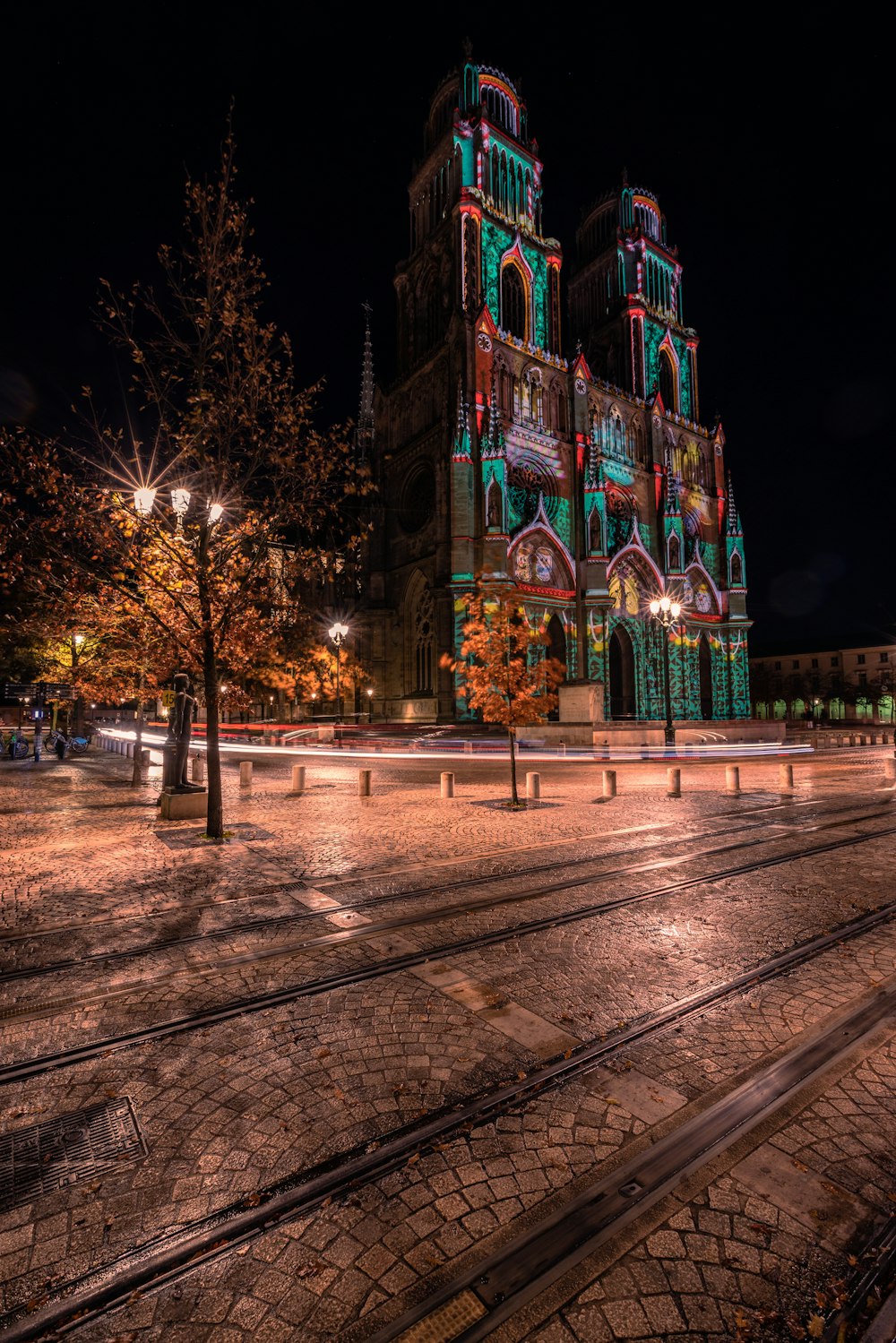 a church lit up at night with a train track in front of it