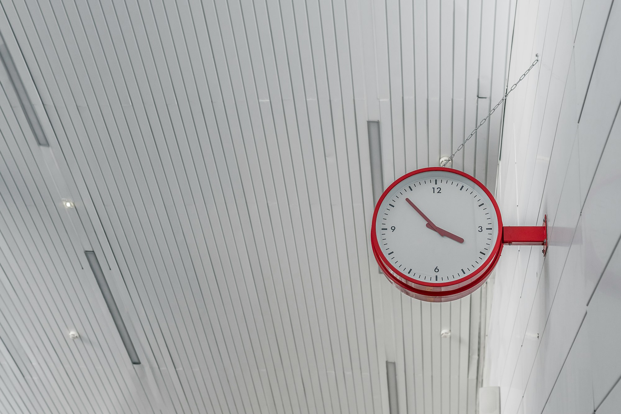 bright red clock on a white background, at the city railway station with copy space