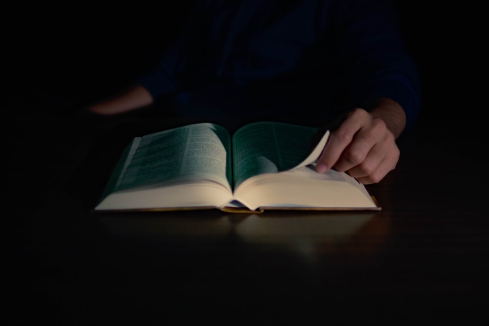 une personne lisant un livre dans le noir