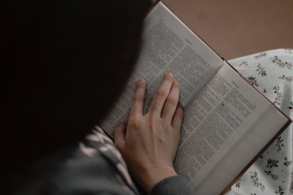 a person reading a book on a bed