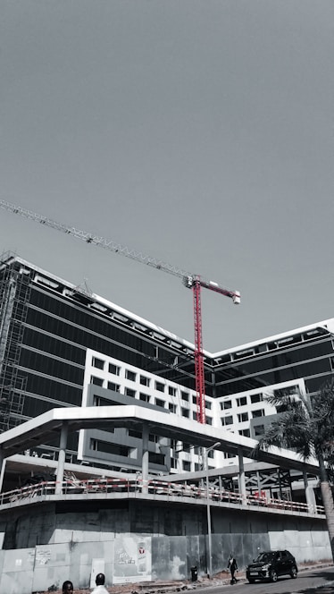 A sleek, modern architectural building under construction with cranes in the background