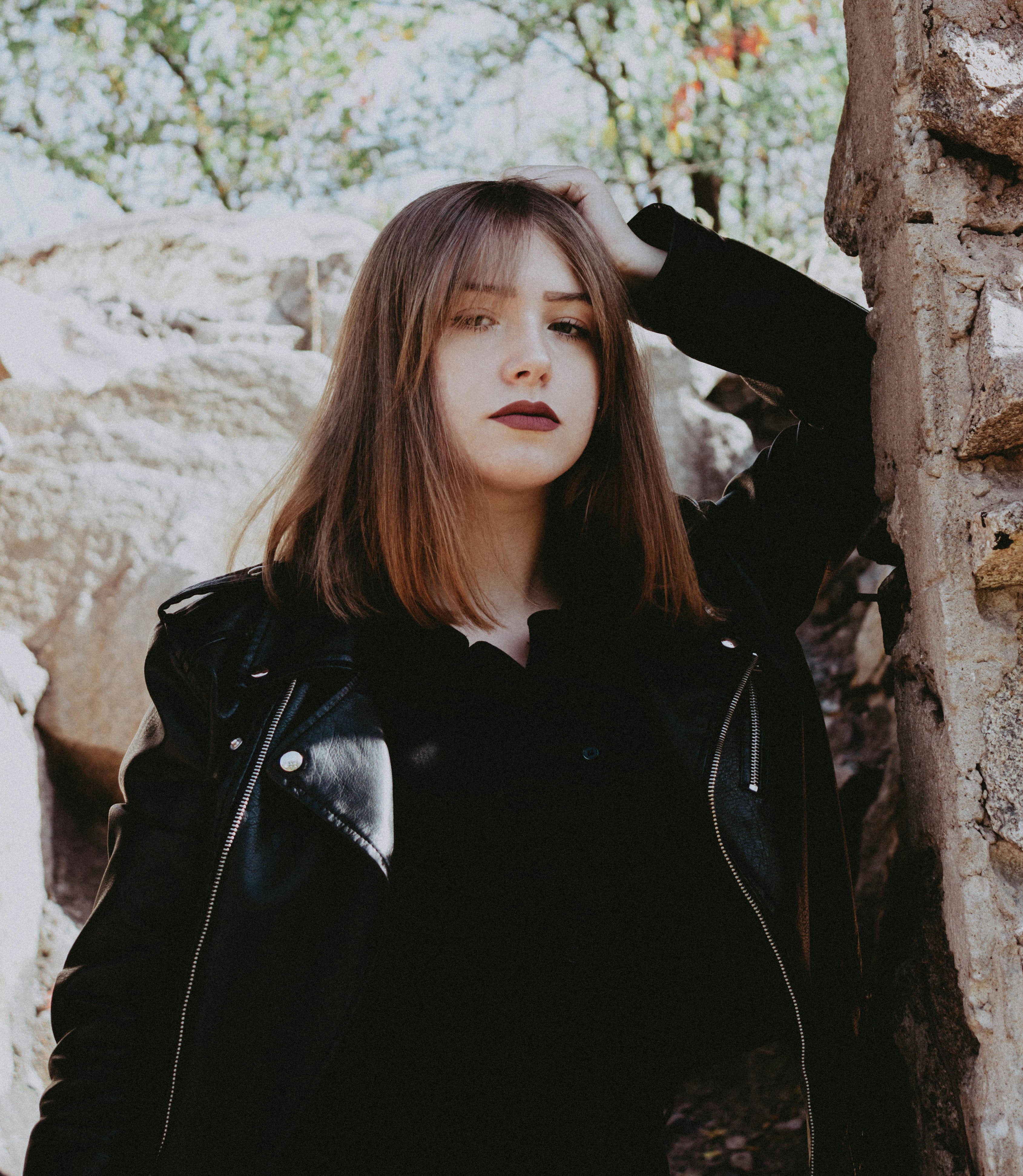 a woman standing next to a stone wall