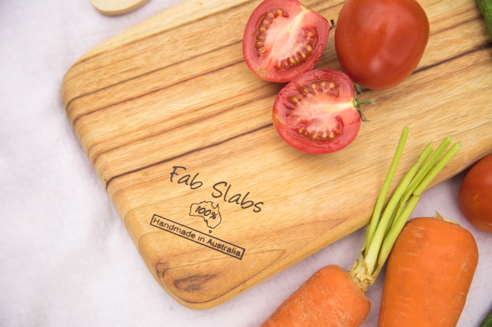 a cutting board with tomatoes and carrots on it