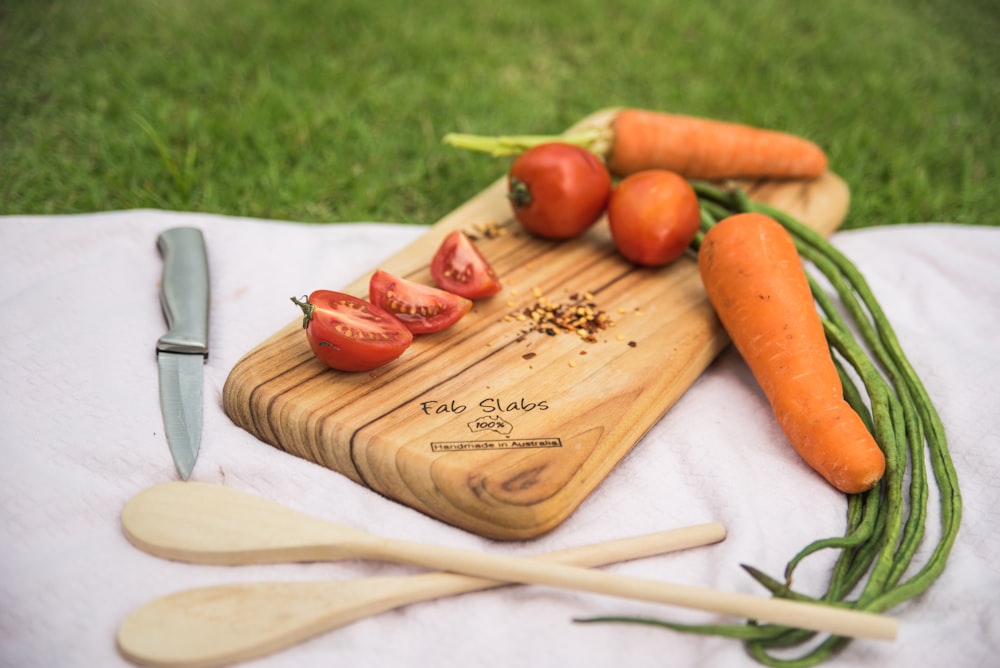 a cutting board with carrots and tomatoes on it