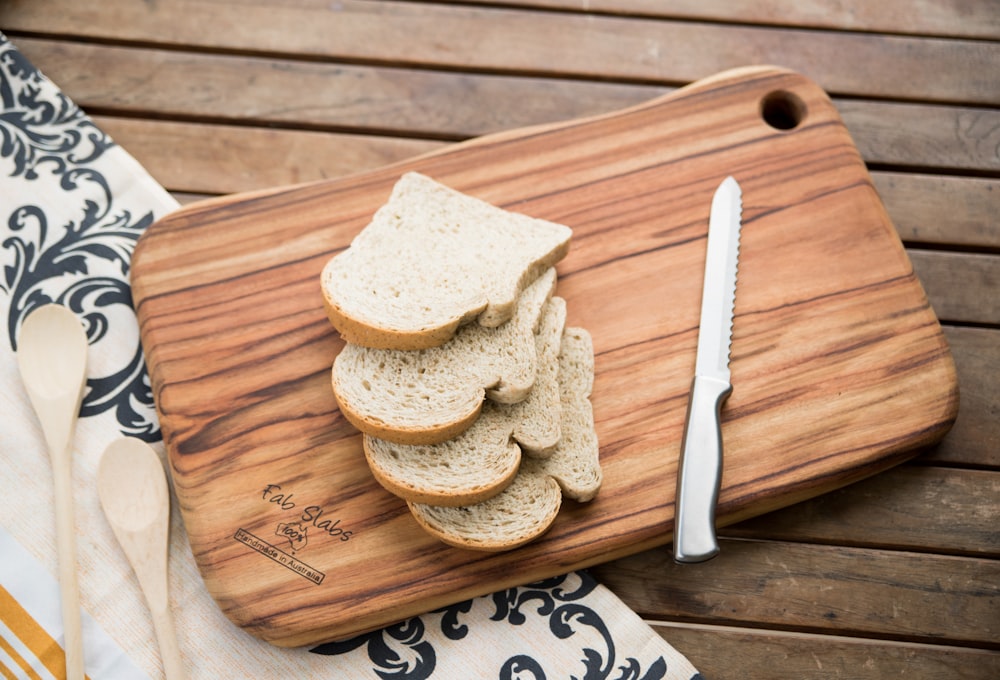 a cutting board topped with sliced bread next to a knife