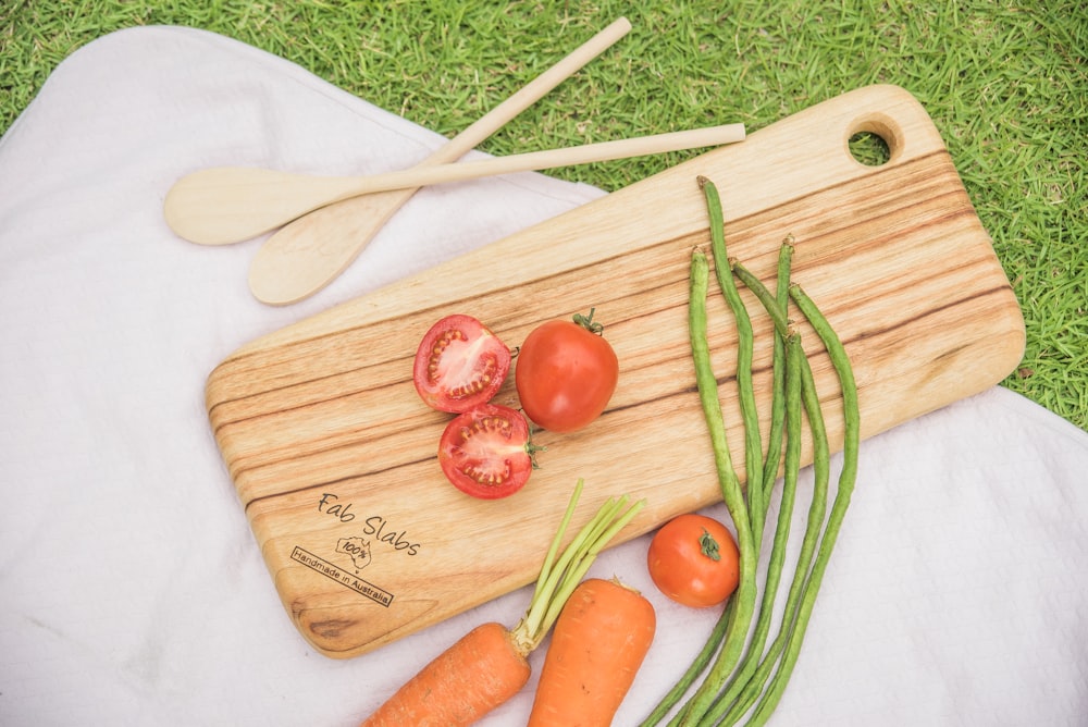 a cutting board with tomatoes, green beans, and carrots