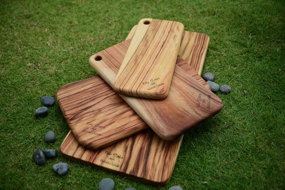 three wooden cutting boards sitting on top of a green field