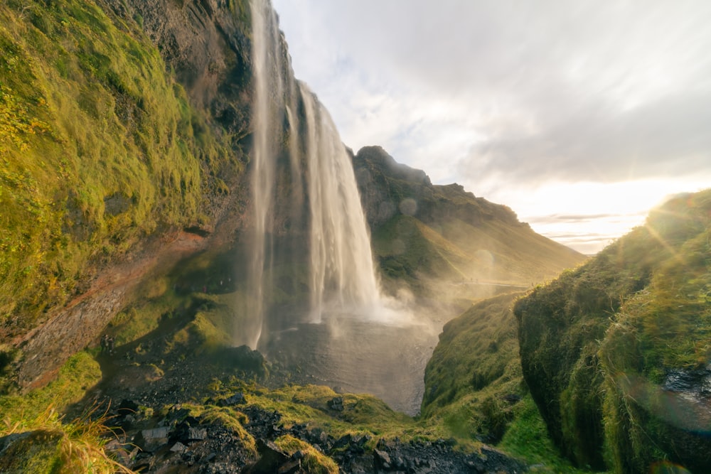 a large waterfall with green moss growing on the side of it