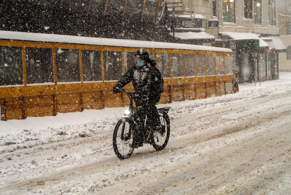 a man riding a bike down a snow covered street