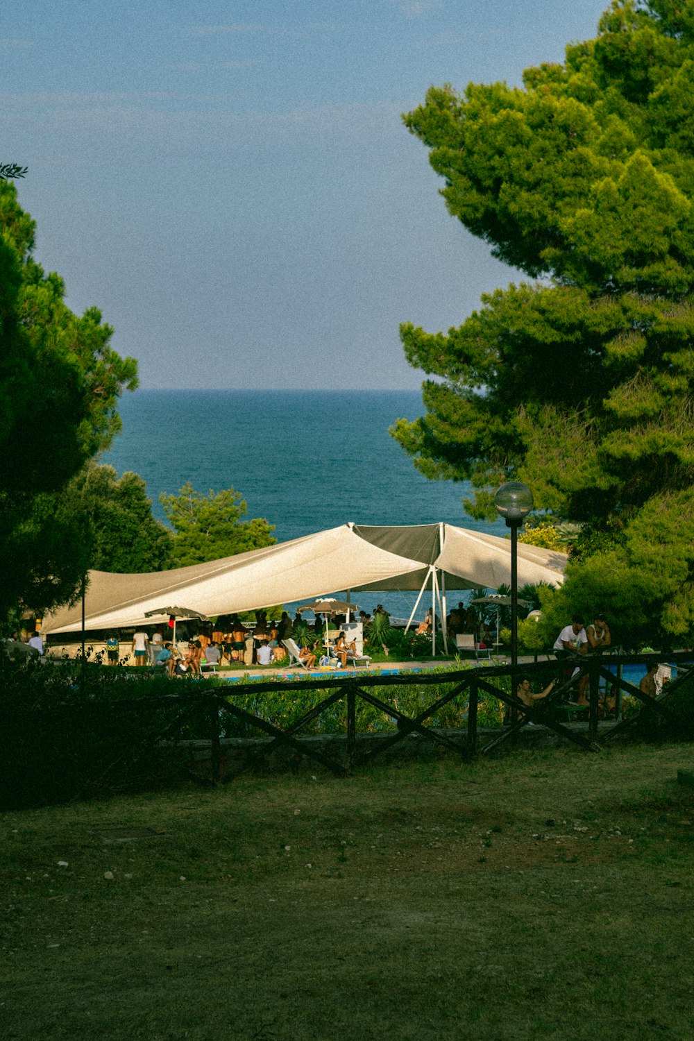 a group of people sitting under a tent next to a body of water