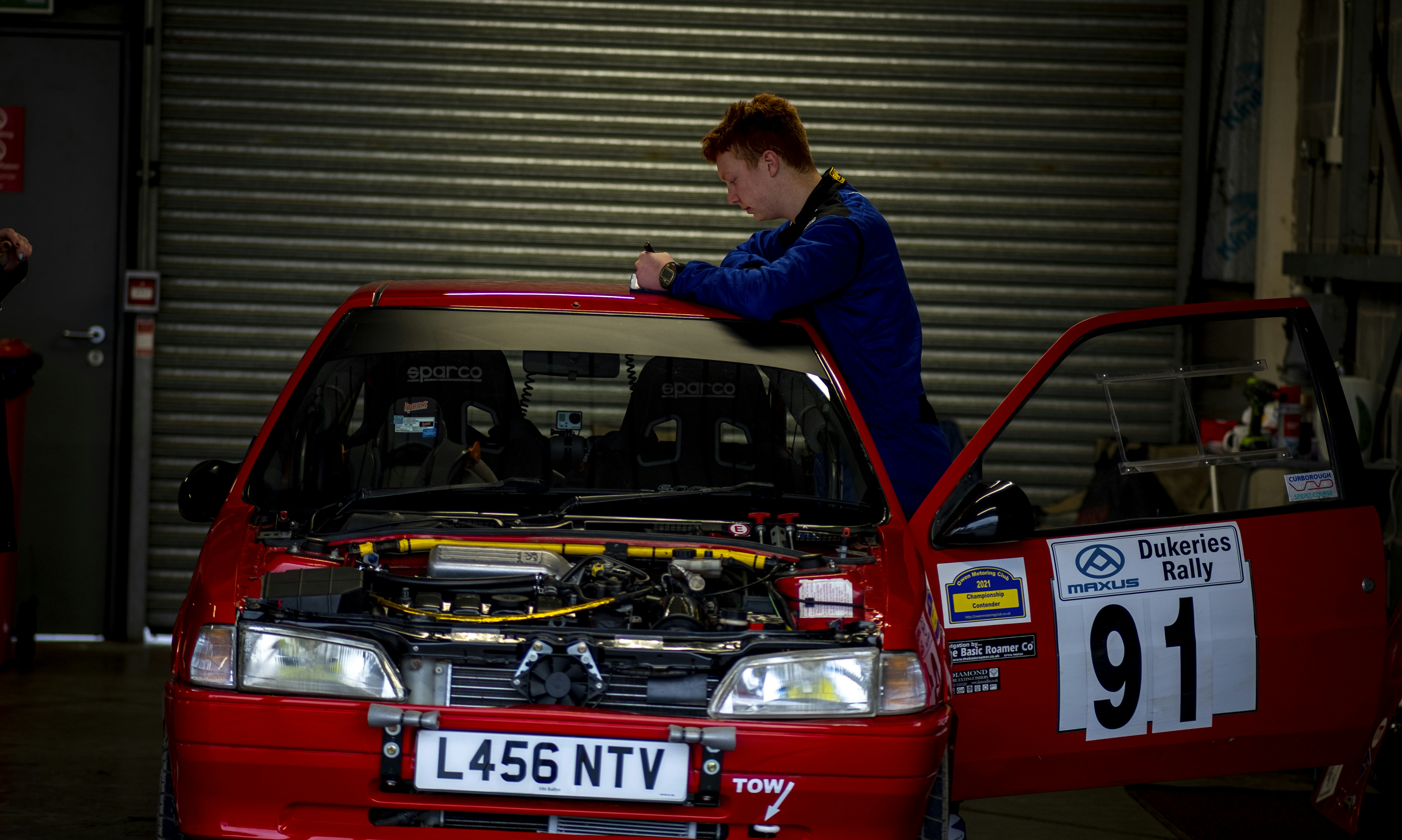 Technician using a multimeter to test a car battery on a workbench