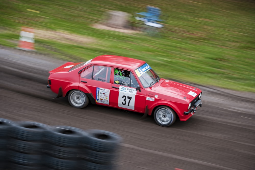 a red car driving down a dirt road