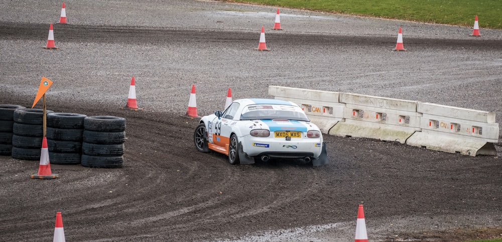 a car driving around a track with orange cones around it