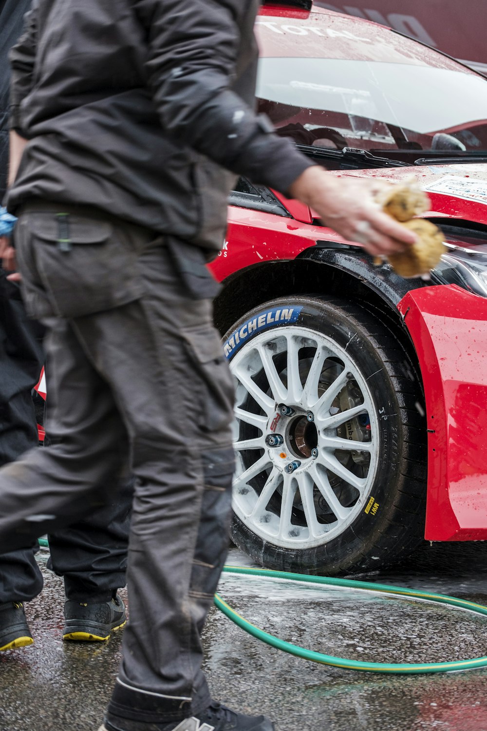 a man is washing a red car with a hose