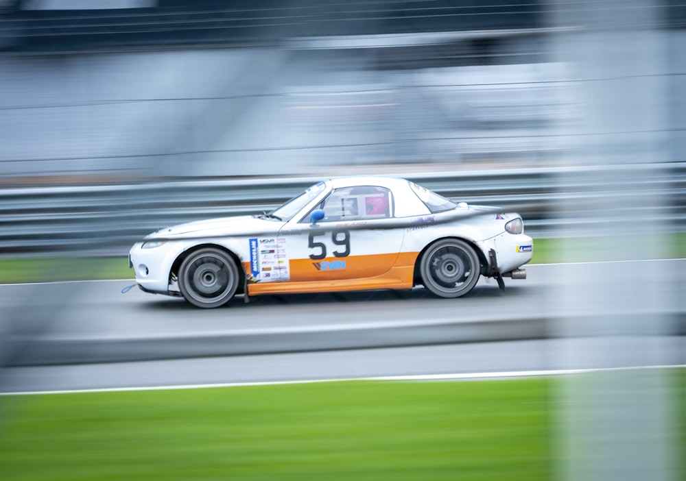 an orange and white car driving down a race track