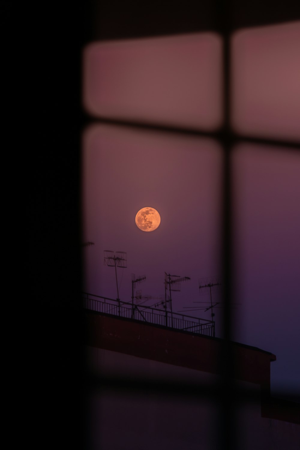 a full moon seen through a window at night