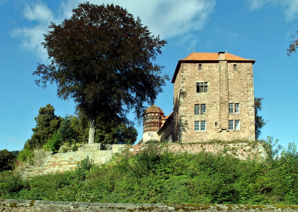 a tall brick building sitting on top of a lush green hillside