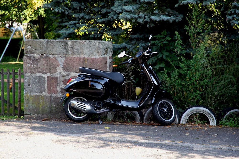 a black scooter parked next to a brick wall