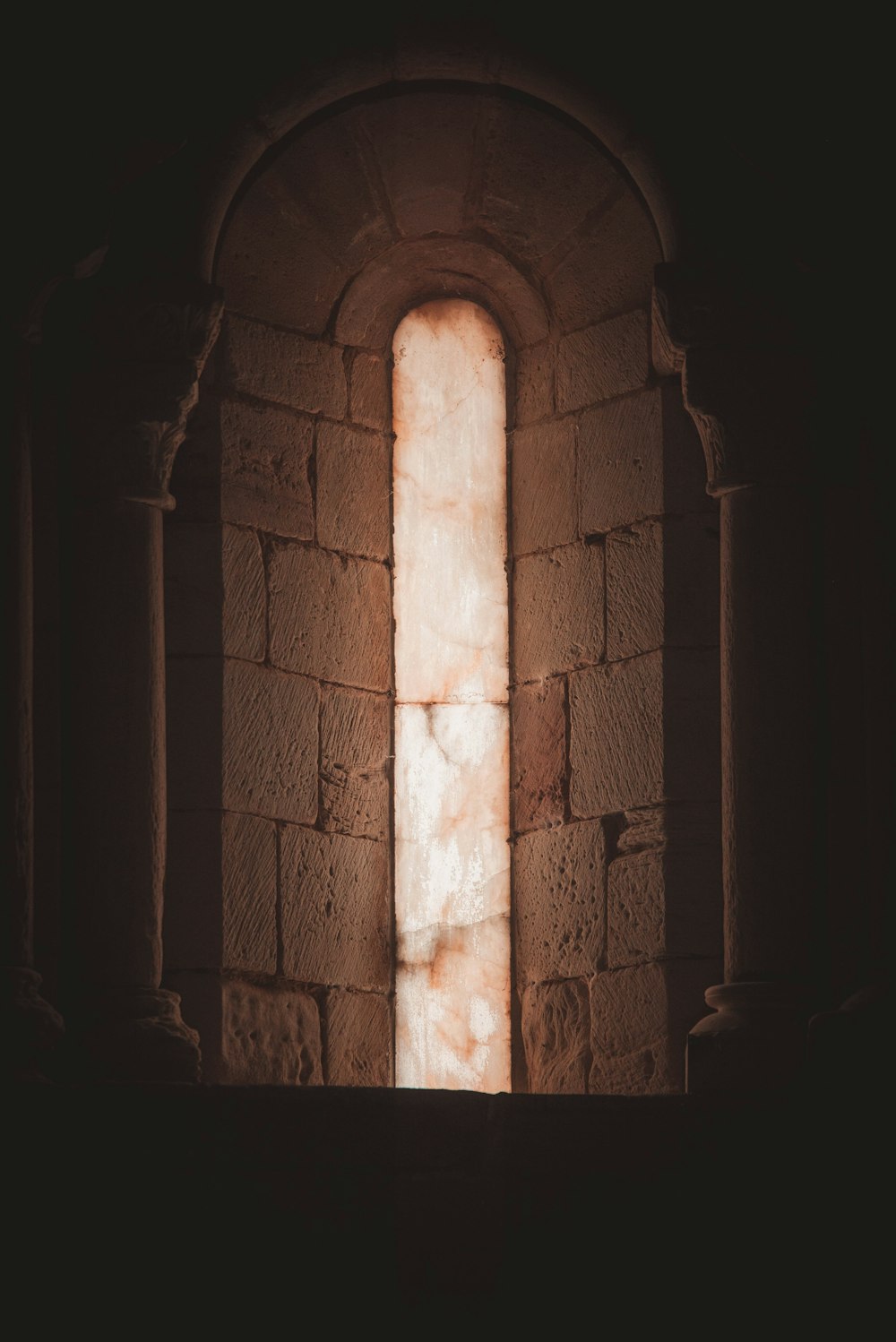 a window in a stone building with a light coming through it