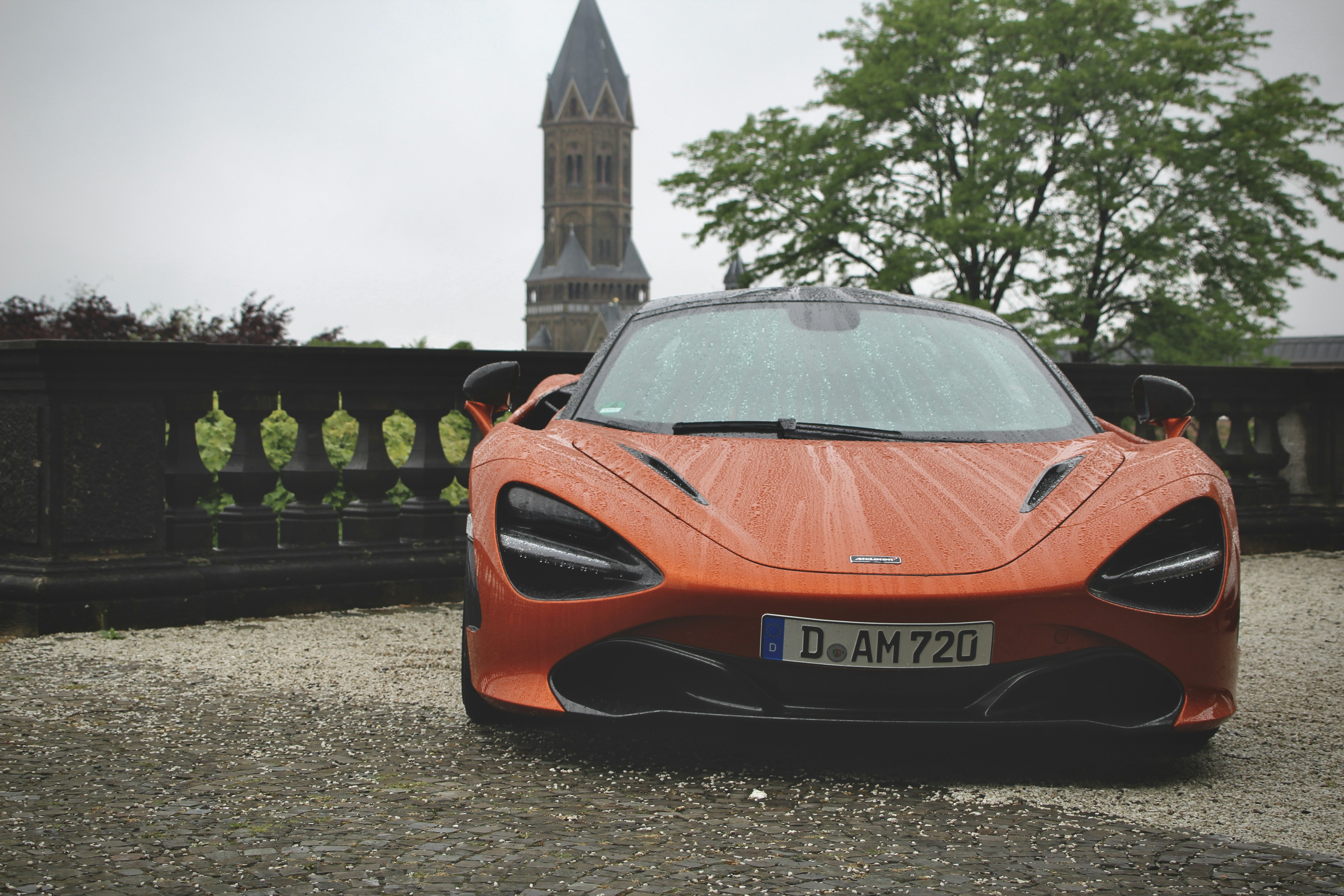 an orange sports car parked in front of a building