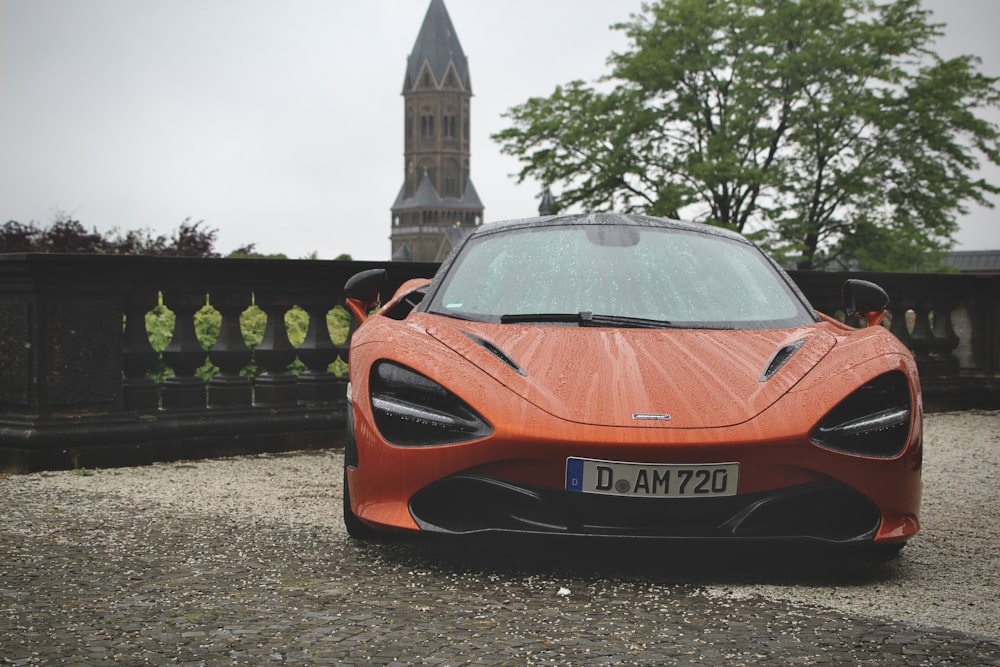 an orange sports car parked in front of a building