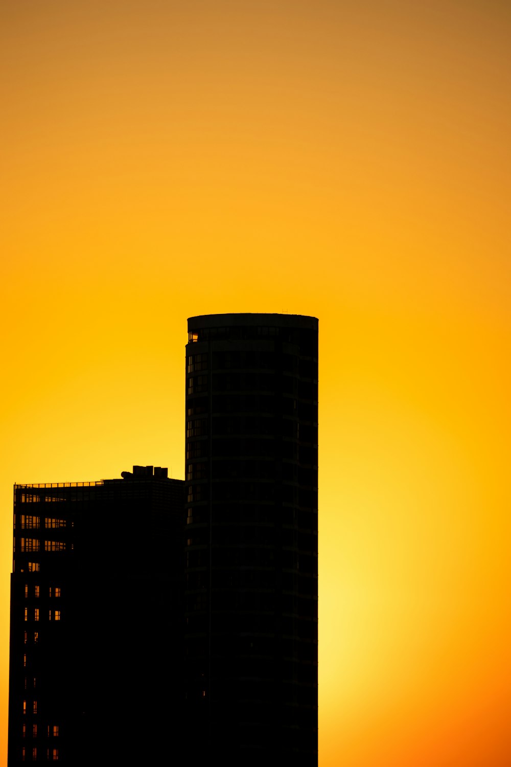 the sun is setting behind a tall building