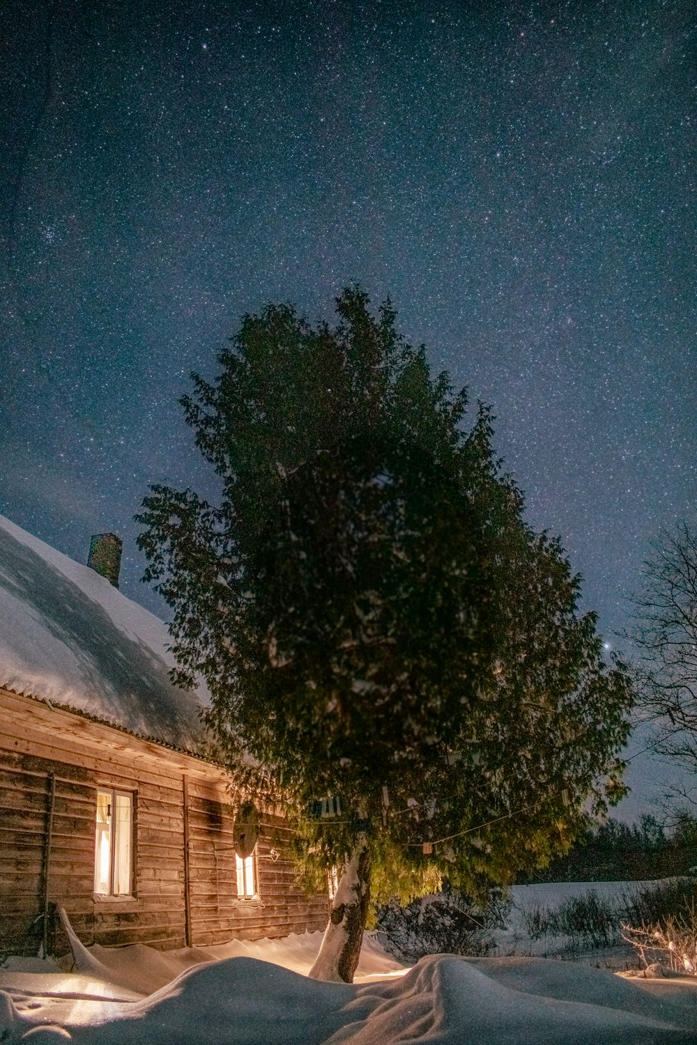 a cabin in the snow under a night sky