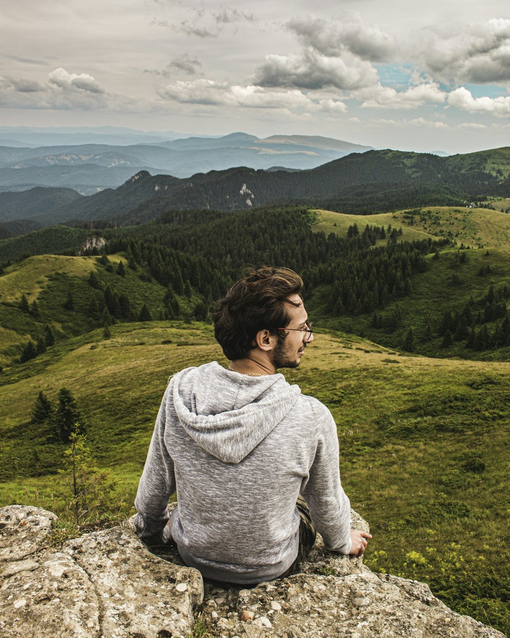 a man sitting on top of a large rock