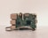 A close-up of a Raspberry Pi board placed on a surface. The green circuit board features various visible components such as USB ports, HDMI port, and several microchips. A ribbon cable is partially visible at the bottom.