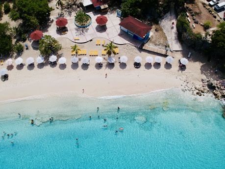 an aerial view of a beach with umbrellas and chairs